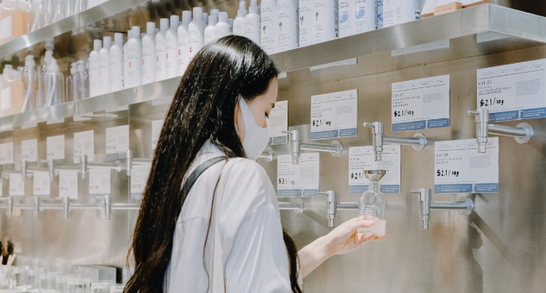 Customer refilling personal care products at Slowood's refill wall.